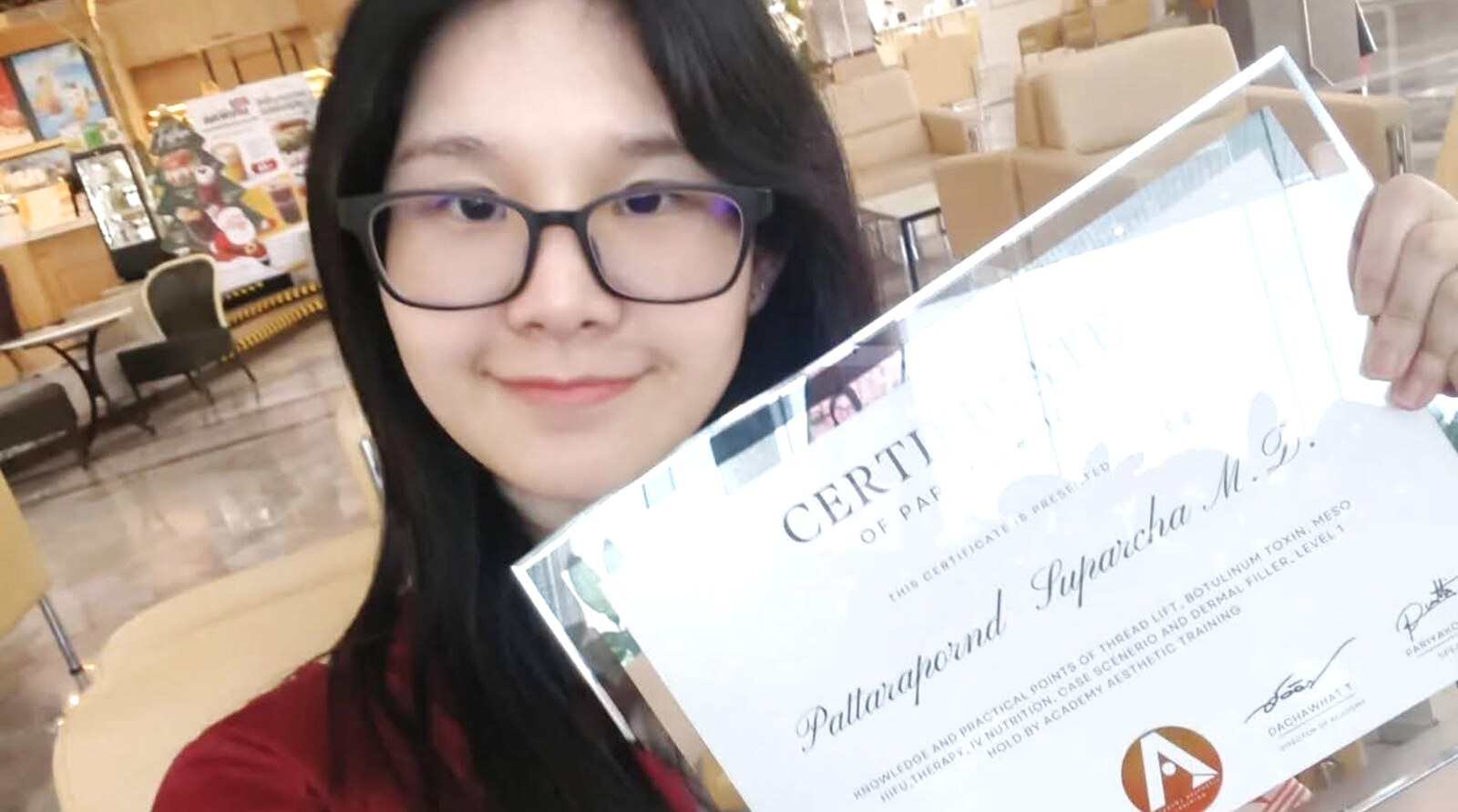 Dr. Pattarapornd Suparcha holding a completion certificate from an aesthetic medicine training course